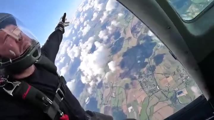 A skydiver in the door of the jump plane over the dropzone